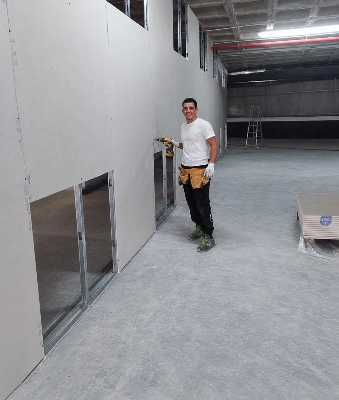 Oficial de Aislamientos Chairi atornillando un tabique de pladur en una nave de Ceuta